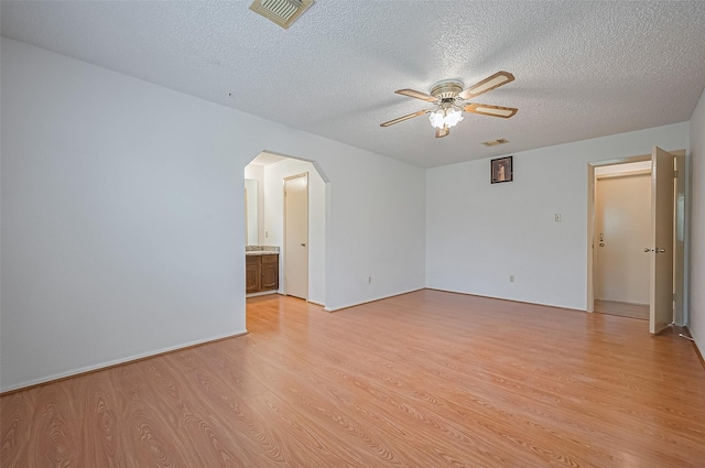 5615 Briarwood Forest Dr, Houston, TX 77088 - empty room with arched walkways, ceiling fan, light wood-style flooring, and a textured ceiling