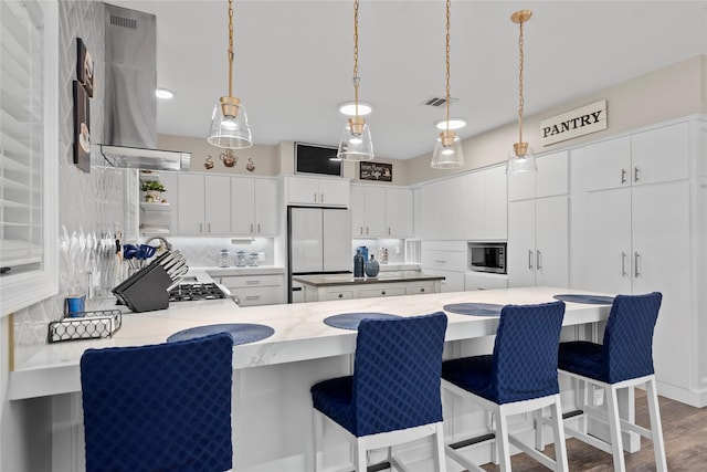 5411 Holly View Dr, Houston, TX 77091 - kitchen with a peninsula, tasteful backsplash, wall chimney range hood, hanging light fixtures, and white cabinets