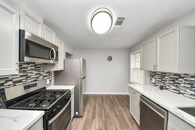 3111 Tanglebriar Dr, Pasadena, TX 77503 - kitchen with stainless steel appliances, light wood finished floors, backsplash, and light stone counters