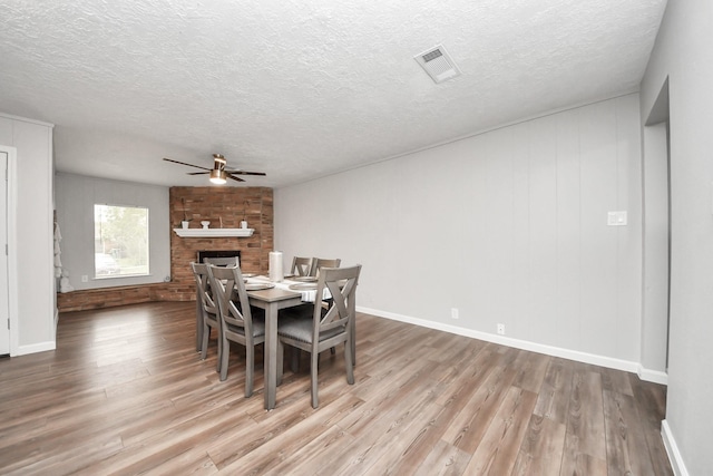 3111 Tanglebriar Dr, Pasadena, TX 77503 - dining space with a ceiling fan, wood finished floors, a textured ceiling, and a large fireplace