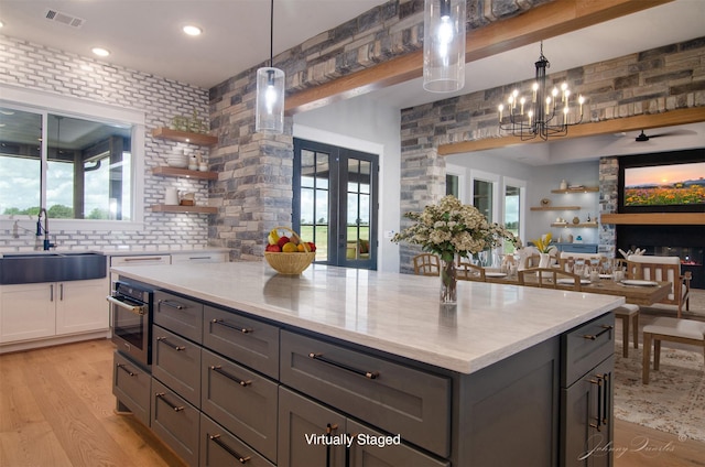 4410 Jozwiak Rd, Chappell Hill, TX 77426 - kitchen with open shelves, gray cabinetry, open floor plan, light wood-style floors, and recessed lighting