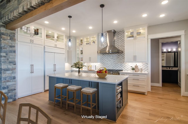 4410 Jozwiak Rd, Chappell Hill, TX 77426 - kitchen with wall chimney exhaust hood, light countertops, white cabinets, tasteful backsplash, and a kitchen island with sink