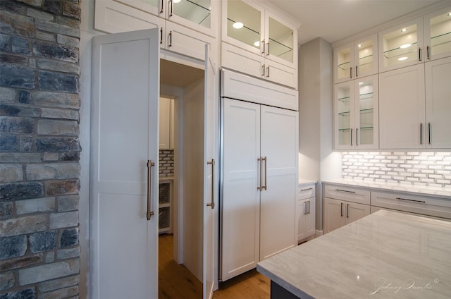4410 Jozwiak Rd, Chappell Hill, TX 77426 - kitchen featuring wood finished floors, paneled refrigerator, white cabinetry, backsplash, and glass insert cabinets