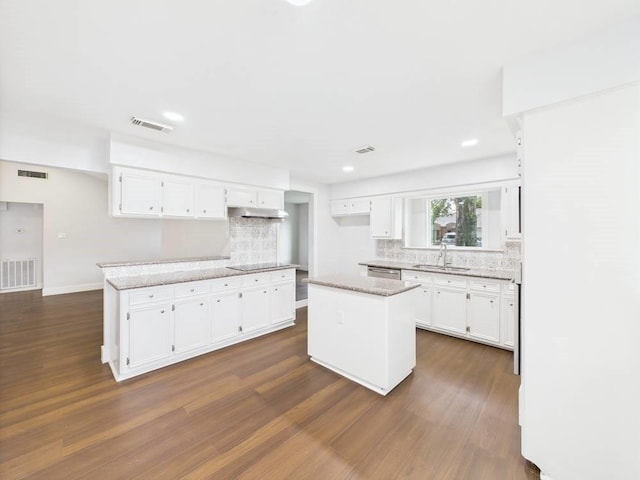 8918 Bold Forest Dr, Houston, TX 77088 - kitchen with backsplash, dark wood-style floors, white cabinetry, under cabinet range hood, and recessed lighting