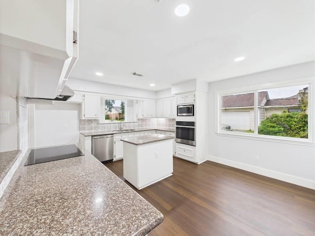 8918 Bold Forest Dr, Houston, TX 77088 - kitchen with appliances with stainless steel finishes, a center island, white cabinetry, tasteful backsplash, and dark wood-style flooring