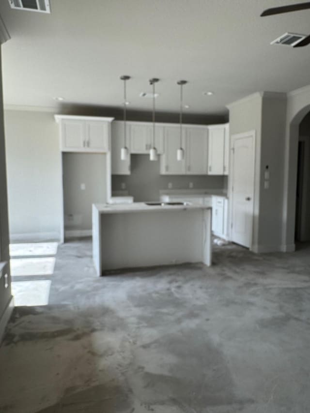5503 Bacher St, Houston, TX 77028 - kitchen featuring white cabinetry, arched walkways, a kitchen island, decorative light fixtures, and concrete flooring