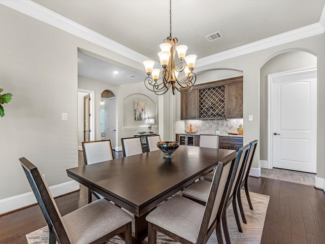 11913 Barryknoll Ln, Houston, TX 77024 - dining room featuring arched walkways, a chandelier, dark wood-type flooring, ornamental molding, and recessed lighting