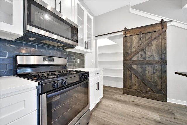 6727 Parker Oaks Ln, Houston, TX 77076 - kitchen featuring stainless steel appliances, white cabinetry, light wood finished floors, and glass insert cabinets