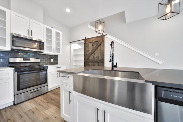 6727 Parker Oaks Ln, Houston, TX 77076 - kitchen featuring appliances with stainless steel finishes, light wood finished floors, white cabinetry, backsplash, and recessed lighting