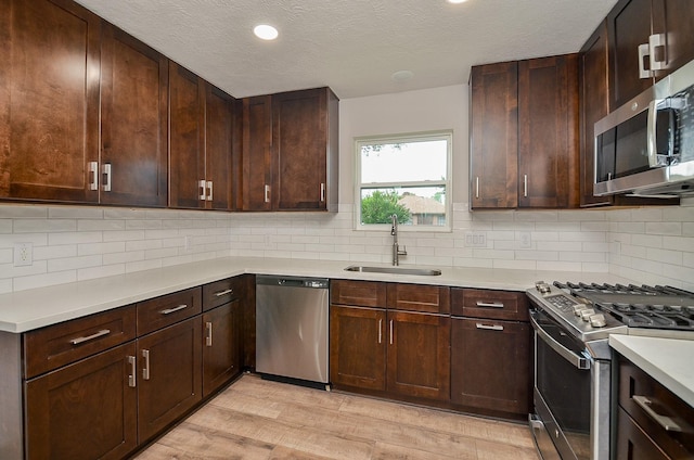 14835 Charlmont Dr, Houston, TX 77083 - kitchen with stainless steel appliances, light wood-style floors, light countertops, decorative backsplash, and a textured ceiling
