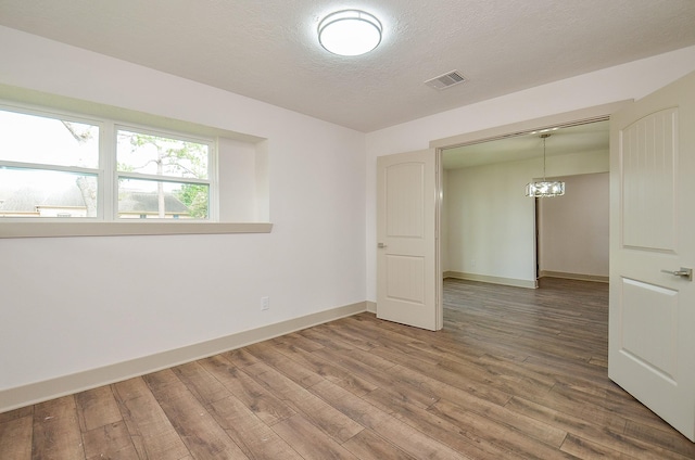 14835 Charlmont Dr, Houston, TX 77083 - empty room with wood finished floors, a chandelier, and a textured ceiling