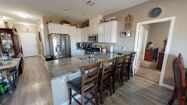 406 Rd 5102 Unit L, Cleveland, TX 77327 - kitchen with stainless steel appliances, light wood-type flooring, dark stone counters, a breakfast bar area, and a textured ceiling