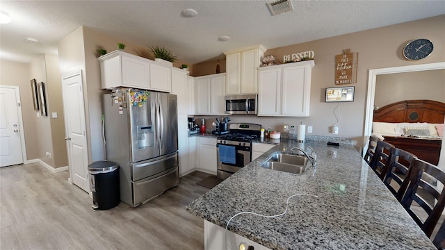 406 Rd 5102 Unit L, Cleveland, TX 77327 - kitchen with stainless steel appliances, light wood finished floors, light stone counters, a peninsula, and white cabinets