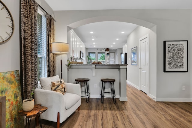 12350 Castano Creek Dr, Humble, TX 77346 - kitchen with arched walkways, wood finished floors, white cabinetry, a kitchen bar, and recessed lighting