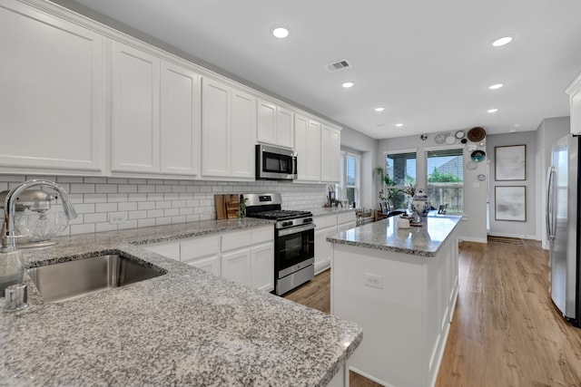 12350 Castano Creek Dr, Humble, TX 77346 - kitchen with stainless steel appliances, a kitchen island, tasteful backsplash, white cabinets, and recessed lighting