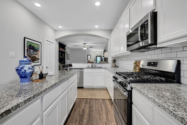 12350 Castano Creek Dr, Humble, TX 77346 - kitchen with stainless steel appliances, arched walkways, a ceiling fan, white cabinets, and dark wood-style flooring