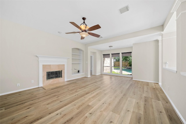 3106 Rainbow Ct, Pearland, TX 77584 - unfurnished living room featuring built in features, light wood-style floors, a fireplace, and a ceiling fan