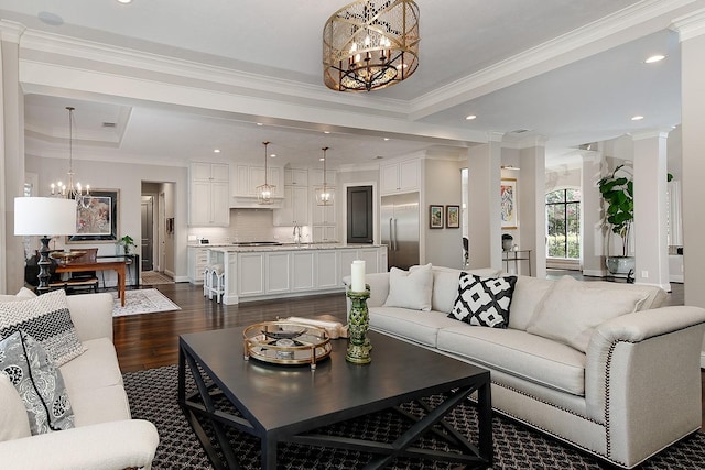 227 Starlight Pl, The Woodlands, TX 77380 - living room featuring a chandelier, dark wood finished floors, crown molding, decorative columns, and a raised ceiling