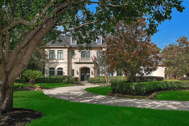 227 Starlight Pl, The Woodlands, TX 77380 - view of front of property with stucco siding, a front lawn, french doors, and a balcony