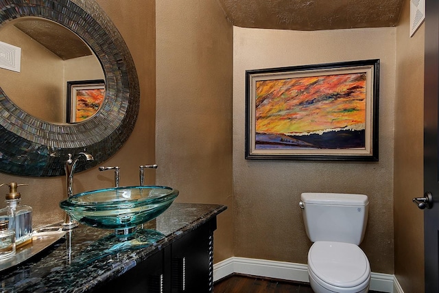 227 Starlight Pl, The Woodlands, TX 77380 - half bathroom featuring wood finished floors, vanity, and a textured wall