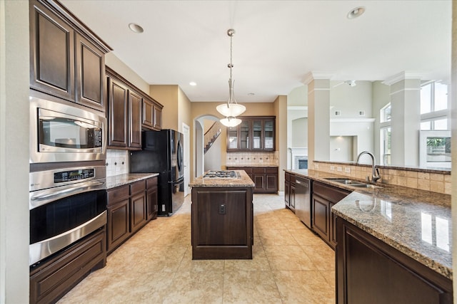 4503 Riley Way Ln, Sugar Land, TX 77479 - kitchen with stainless steel appliances, decorative backsplash, dark brown cabinetry, a kitchen island, and light stone counters