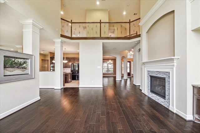 4503 Riley Way Ln, Sugar Land, TX 77479 - unfurnished living room with a fireplace, dark wood-type flooring, a towering ceiling, and arched walkways