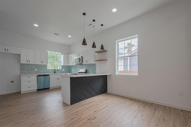 1014 13th St, Galveston, TX 77550 - kitchen featuring appliances with stainless steel finishes, white cabinetry, decorative backsplash, light wood-style flooring, and light countertops