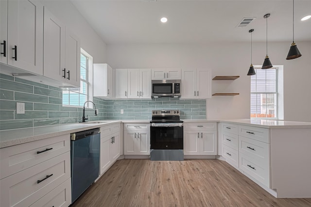 1014 13th St, Galveston, TX 77550 - kitchen featuring stainless steel appliances, a peninsula, light wood finished floors, light countertops, and white cabinets