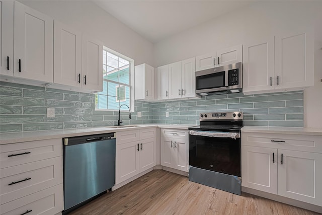 1014 13th St, Galveston, TX 77550 - kitchen featuring stainless steel appliances, light countertops, white cabinetry, and light wood finished floors