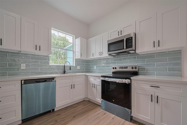 1014 13th St, Galveston, TX 77550 - kitchen featuring stainless steel appliances, light countertops, white cabinetry, light wood-style floors, and backsplash