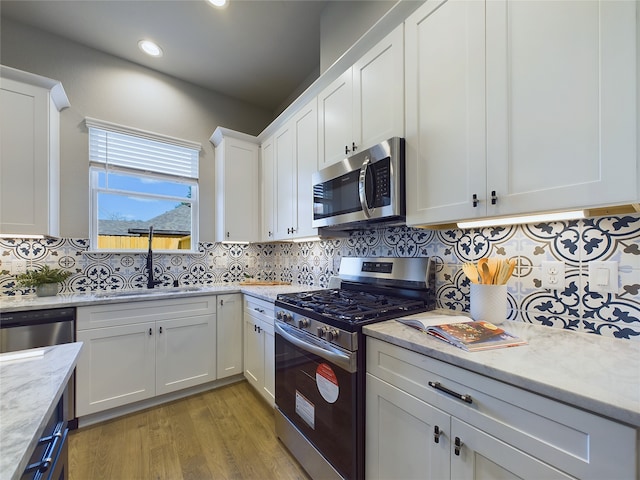 5022 Broom St, Houston, TX 77091 - kitchen with stainless steel appliances, light wood-style floors, white cabinetry, decorative backsplash, and light stone countertops