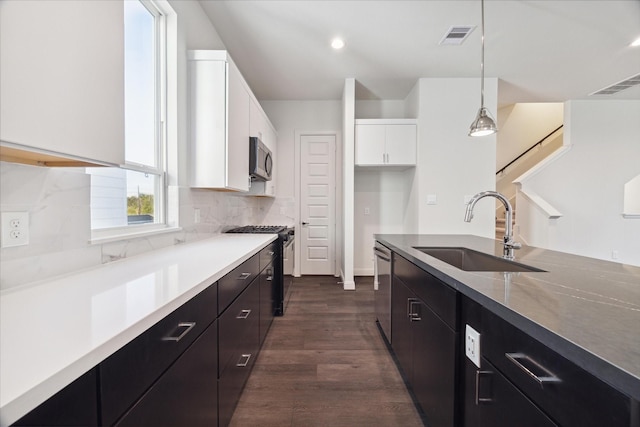 1805 Mills St, Houston, TX 77026 - kitchen with stainless steel appliances, white cabinets, decorative light fixtures, dark wood-type flooring, and decorative backsplash
