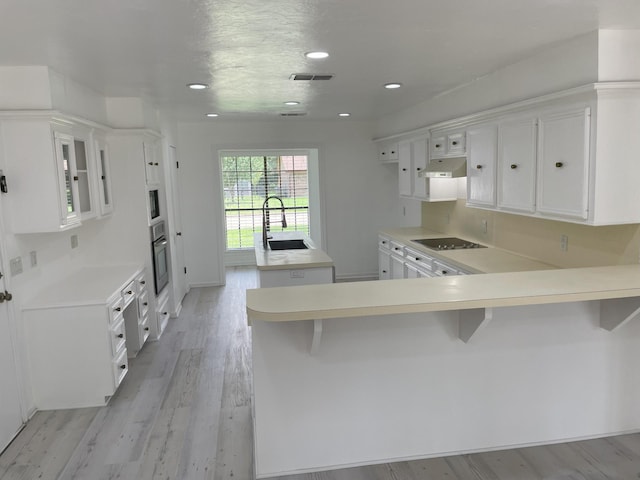3419 Willowrun Dr, Montgomery, TX 77356 - kitchen featuring under cabinet range hood, stainless steel oven, a center island with sink, black electric stovetop, and light countertops