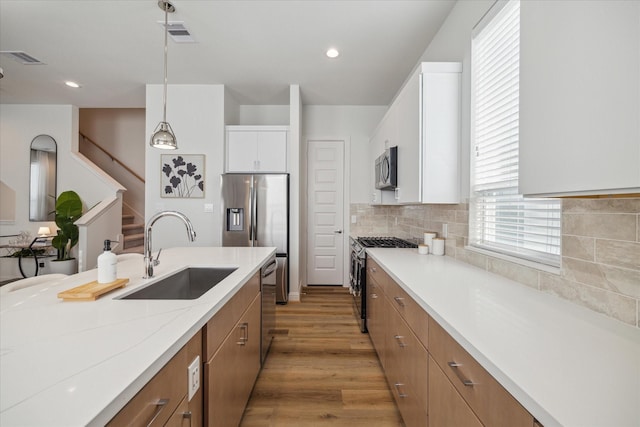1804 Elysian St, Houston, TX 77026 - kitchen with stainless steel appliances, decorative backsplash, pendant lighting, light wood finished floors, and white cabinetry