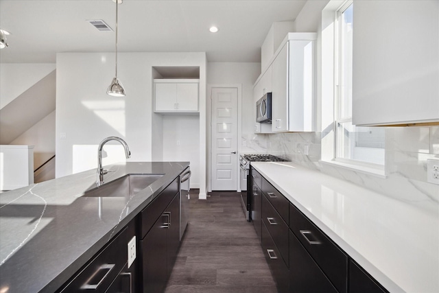 1812 Elysian St, Houston, TX 77026 - kitchen featuring appliances with stainless steel finishes, white cabinets, dark wood-style floors, pendant lighting, and light stone counters
