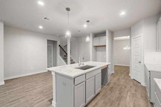 15215 Statice Trl, Houston, TX 77044 - kitchen with light wood-type flooring, recessed lighting, light stone counters, pendant lighting, and a center island with sink