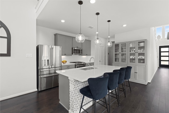 8814 Riverton Ridge Rd, Cypress, TX 77433 - kitchen featuring appliances with stainless steel finishes, gray cabinets, dark wood finished floors, light countertops, and a kitchen bar
