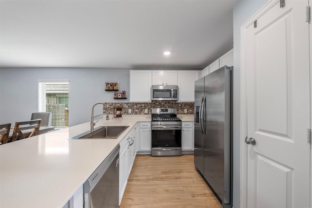 19919 Epirus Shores Dr, Hockley, TX 77447 - kitchen with stainless steel appliances, light countertops, white cabinetry, a peninsula, and light wood-style floors