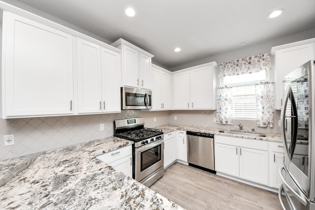 12306 Belhaven Terrace Dr, Houston, TX 77044 - kitchen with appliances with stainless steel finishes, light stone countertops, white cabinets, recessed lighting, and tasteful backsplash