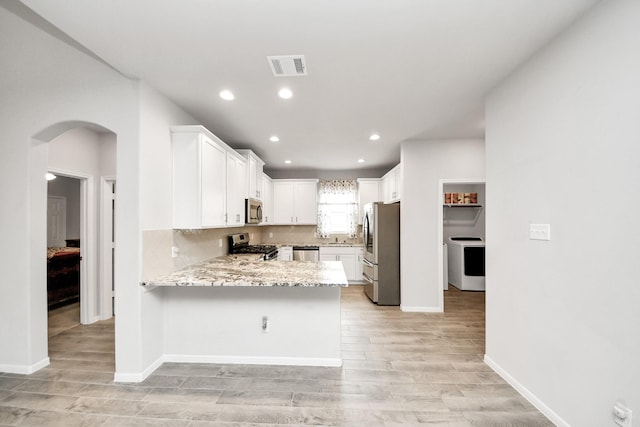 12306 Belhaven Terrace Dr, Houston, TX 77044 - kitchen with appliances with stainless steel finishes, a peninsula, light wood finished floors, recessed lighting, and arched walkways