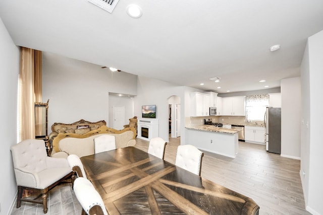 12306 Belhaven Terrace Dr, Houston, TX 77044 - dining space with arched walkways, light wood-type flooring, recessed lighting, and a fireplace