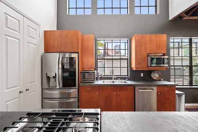 2614 Yoakum Blvd, Houston, TX 77006 - kitchen with stainless steel appliances, a towering ceiling, brown cabinetry, dark countertops, and plenty of natural light