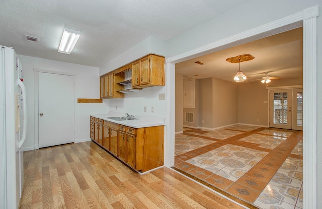 10131 Tangiers Rd, Houston, TX 77041 - kitchen with freestanding refrigerator, brown cabinets, light countertops, ceiling fan, and hanging light fixtures