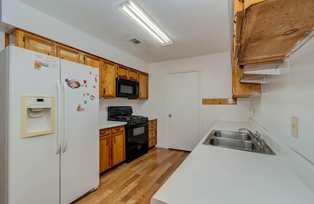 10131 Tangiers Rd, Houston, TX 77041 - kitchen with black appliances, light wood-type flooring, brown cabinetry, and light countertops