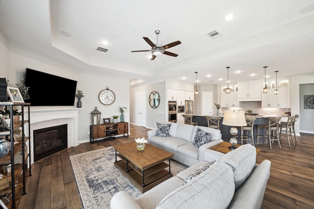 5946 Wedgewood Heights Way, Houston, TX 77059 - living room with a ceiling fan, dark wood-style flooring, recessed lighting, a tile fireplace, and a tray ceiling