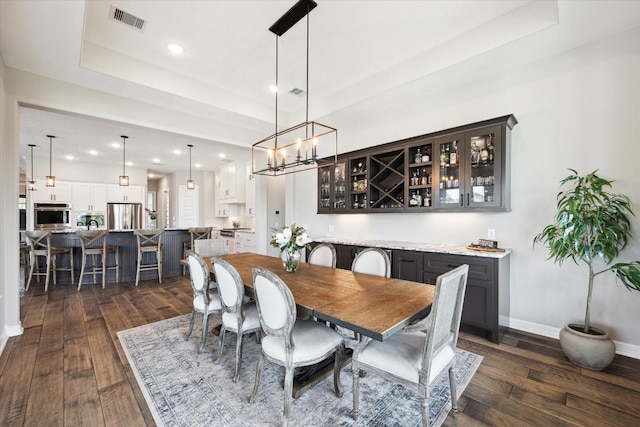 5946 Wedgewood Heights Way, Houston, TX 77059 - dining room featuring dark wood-style flooring, recessed lighting, a chandelier, a raised ceiling, and bar