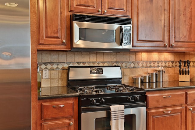 826 E 29th St, Houston, TX 77009 - kitchen featuring stainless steel appliances, backsplash, dark countertops, and brown cabinets