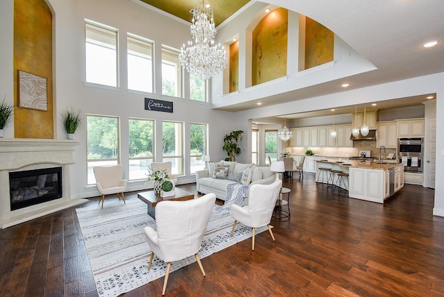 5450 Pudman River Ln, Sugar Land, TX 77479 - living area featuring a chandelier, a fireplace, dark wood-style floors, recessed lighting, and a towering ceiling