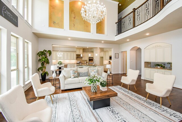 5450 Pudman River Ln, Sugar Land, TX 77479 - living room featuring arched walkways, a high ceiling, a chandelier, dark wood-style floors, and recessed lighting