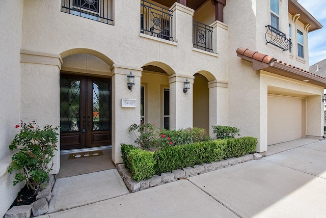 5450 Pudman River Ln, Sugar Land, TX 77479 - view of exterior entry featuring french doors, an attached garage, stucco siding, concrete driveway, and a balcony